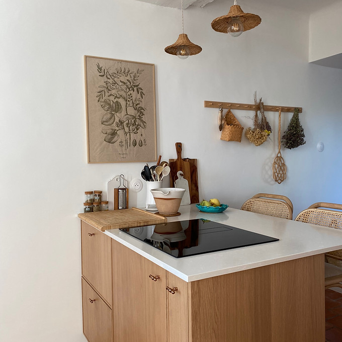 Un ilôt central en bois dans la cuisine avec plan de travail sur mesure et tabouret en bois et rotin
