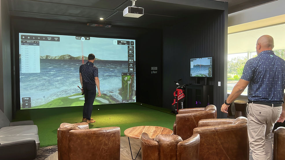 Indoor golf lounge with leather chairs, Uneekor tracking system, and large simulator screen showing GSPro gameplay — Golfsim Australia install.