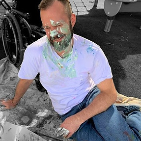 This image depicts Cody joyfully covered in paint, highlighting a creative and interactive therapeutic environment.