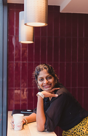 Prarthana sitting in front of a window with a cup of tea in London cafe