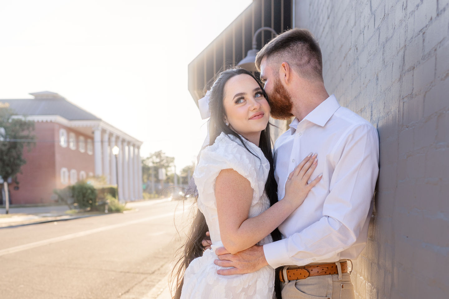 Engaged Couple taking pictures by white brick wall in Lake City Florida
