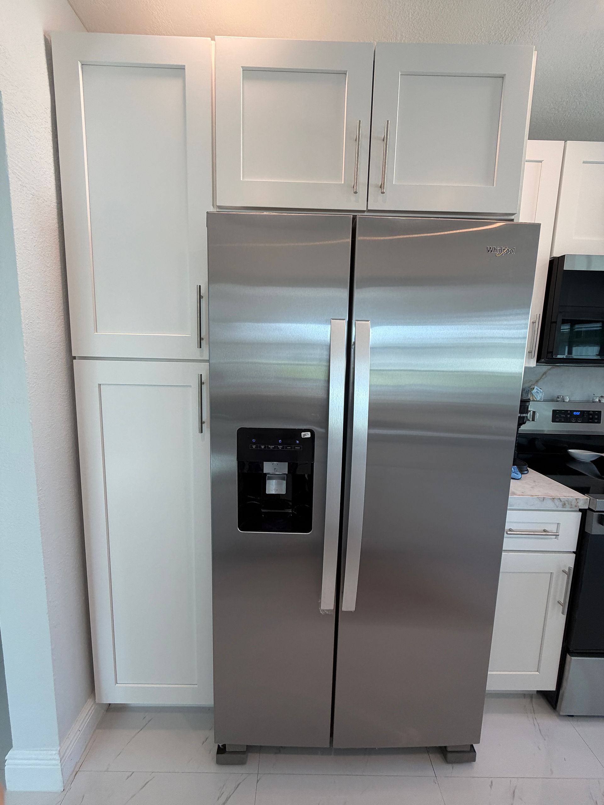 Custom pantry cabinets flanking Whirlpool refrigerator, fire restoration project