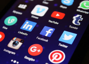 Close-up of a smartphone screen showing various social media app icons such as Facebook and Twitter