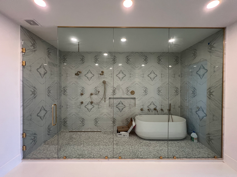 A contemporary shower glass design featuring floor-to-ceiling panels paired with elegant brushed brass hardware, creating a luxurious and seamless spa-like experience