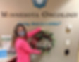 Woman in mask holding winter wreath with word hope beneath wall sign that reads Minnesota Oncology Caring, down to a science.