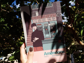 Pessoa segurando o livro “Amêndoas” de Won-pyung Sohn sob a luz do sol, com árvores ao fundo, promovendo literatura asiática contemporânea e temas sobre neurodiversidade.