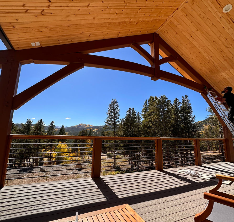 Rustic timber frame deck overlooks autumn trees under a bright blue sky.