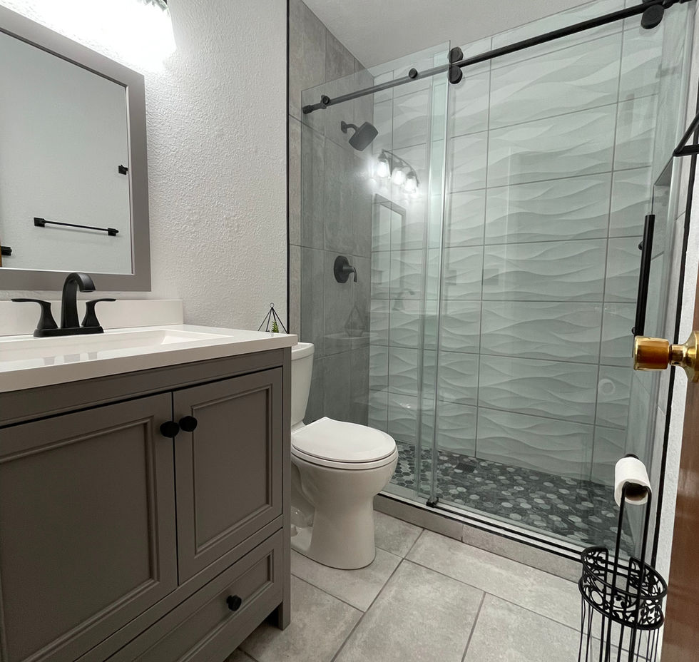 Modern bathroom with gray vanity, toilet, and walk-in glass shower.