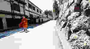 A buddhist monk in traditional orange robes, walking down a street in Koyasan, Japan