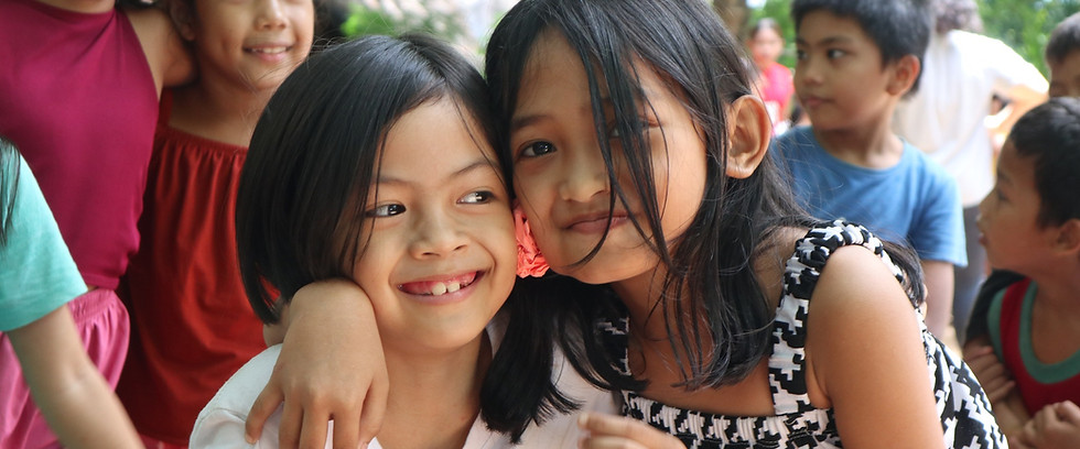 Portrait of two young girls hugging each other and smiling.