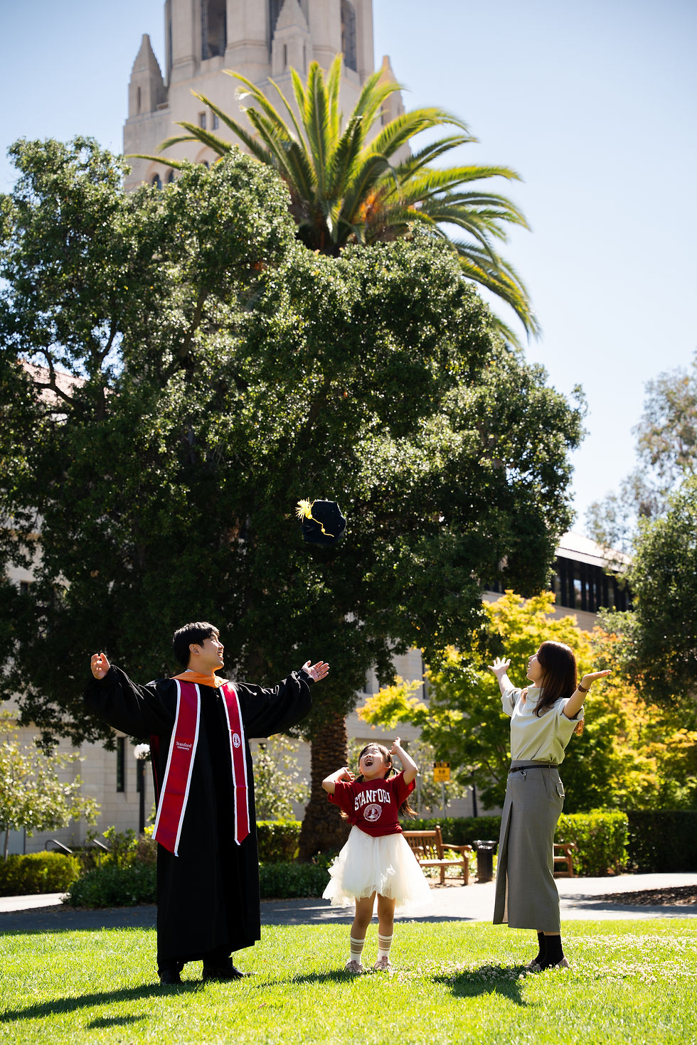 Eye-level view of a Stanford University student in cap and gown smiling with family in the background