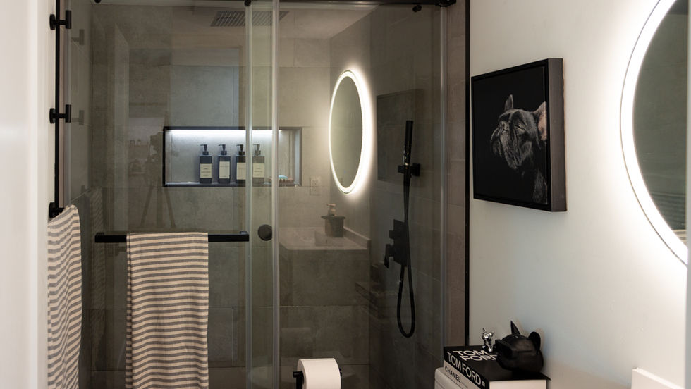 Modern bathroom with glass shower and circular mirror.