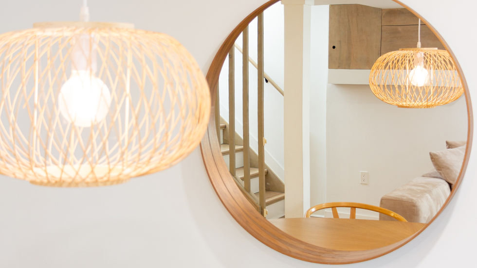 Round mirror reflecting modern interior with hanging light.