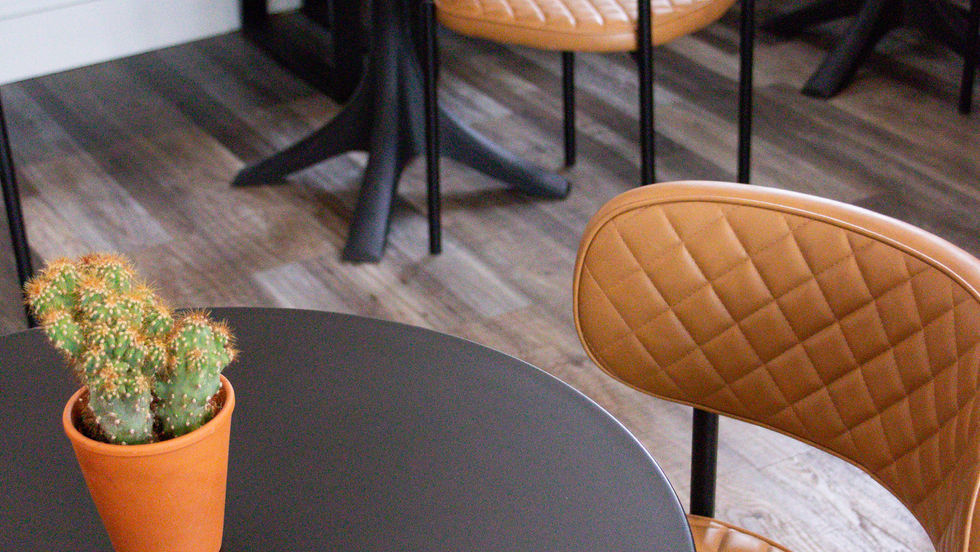 Cafe interior with quilted chairs and small potted plant.