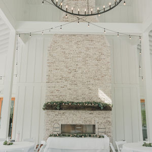 White tablecloths and brick fireplace at reception hall  at  rustic barn wedding venue