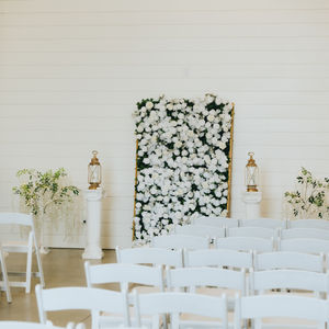 wedding ceremony site with white floral arrangement and white shiplap wall