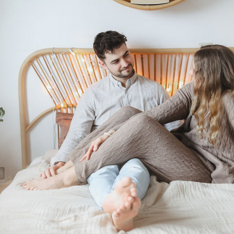 Pärchen sitzt kuschelnd auf dem Bett