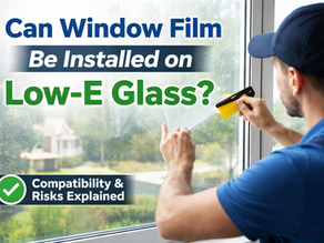 Professional window film installer applying film to a residential Low-E glass window, illustrating compatibility and installation concerns for home window tinting.
