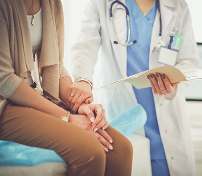 Doctor holding wrist of female patient.