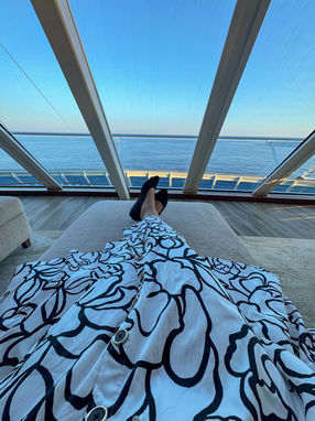 The bottom of a black and white dress with feet and an ocean view from a ship.