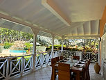 Covered outdoor dining patio overlooking the pool and gardens at The Lauren Taylor Villa