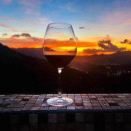 Wine glass overlooking a sunset across the Northern Range at Valli Hai Estate