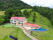 Wide aerial view of The White House surrounded by lawns and Northern Range scenery