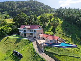 Aerial side view of The White House with pool and forested mountain backdrop