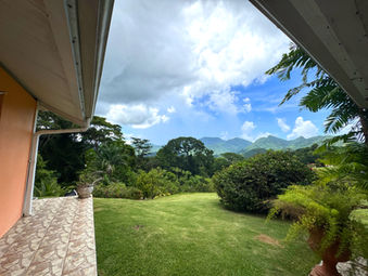 Green lawn and tropical gardens beside Drogeda with Northern Range views