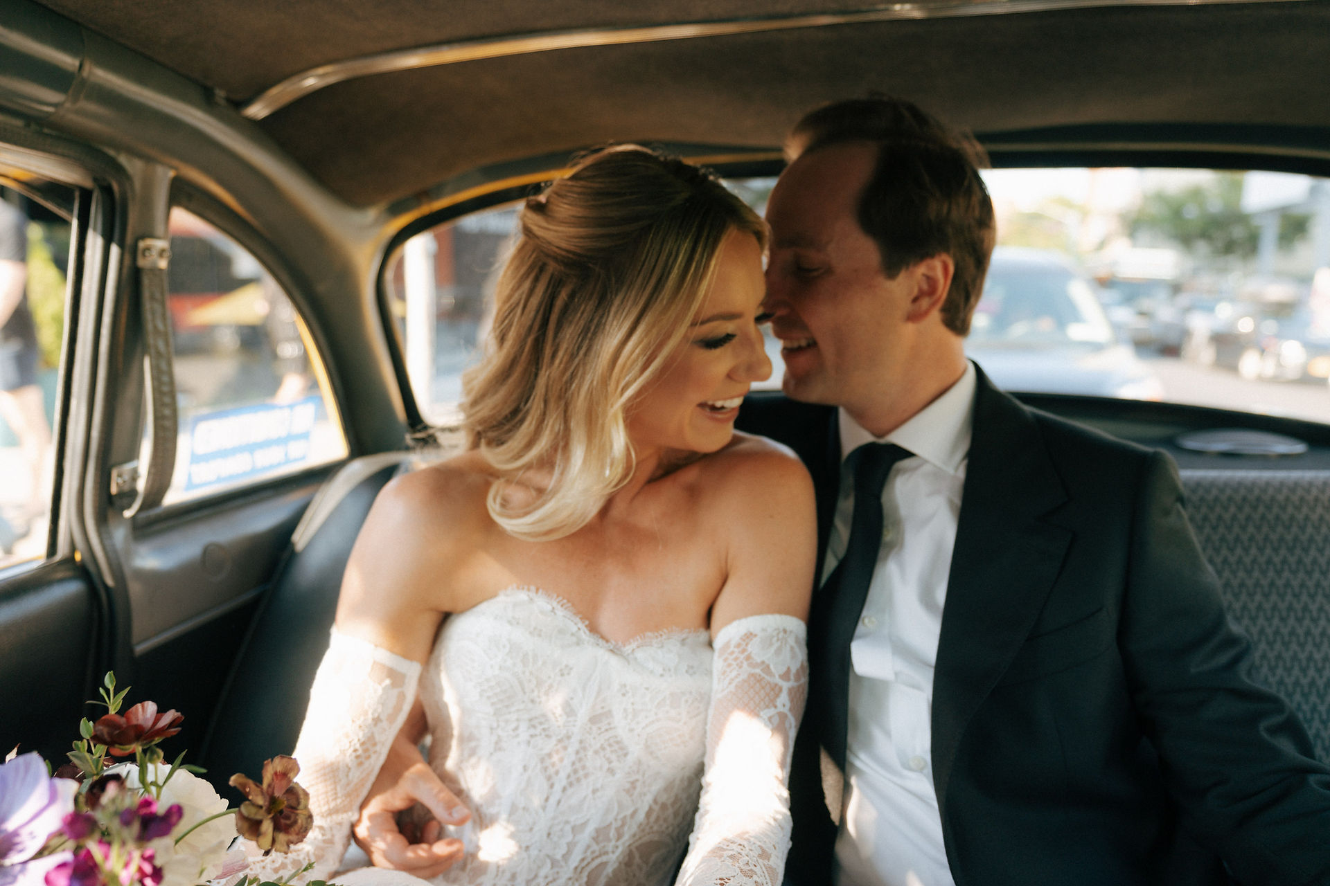 Bride and groom laughing inside vintage car during intimate NYC wedding portraits