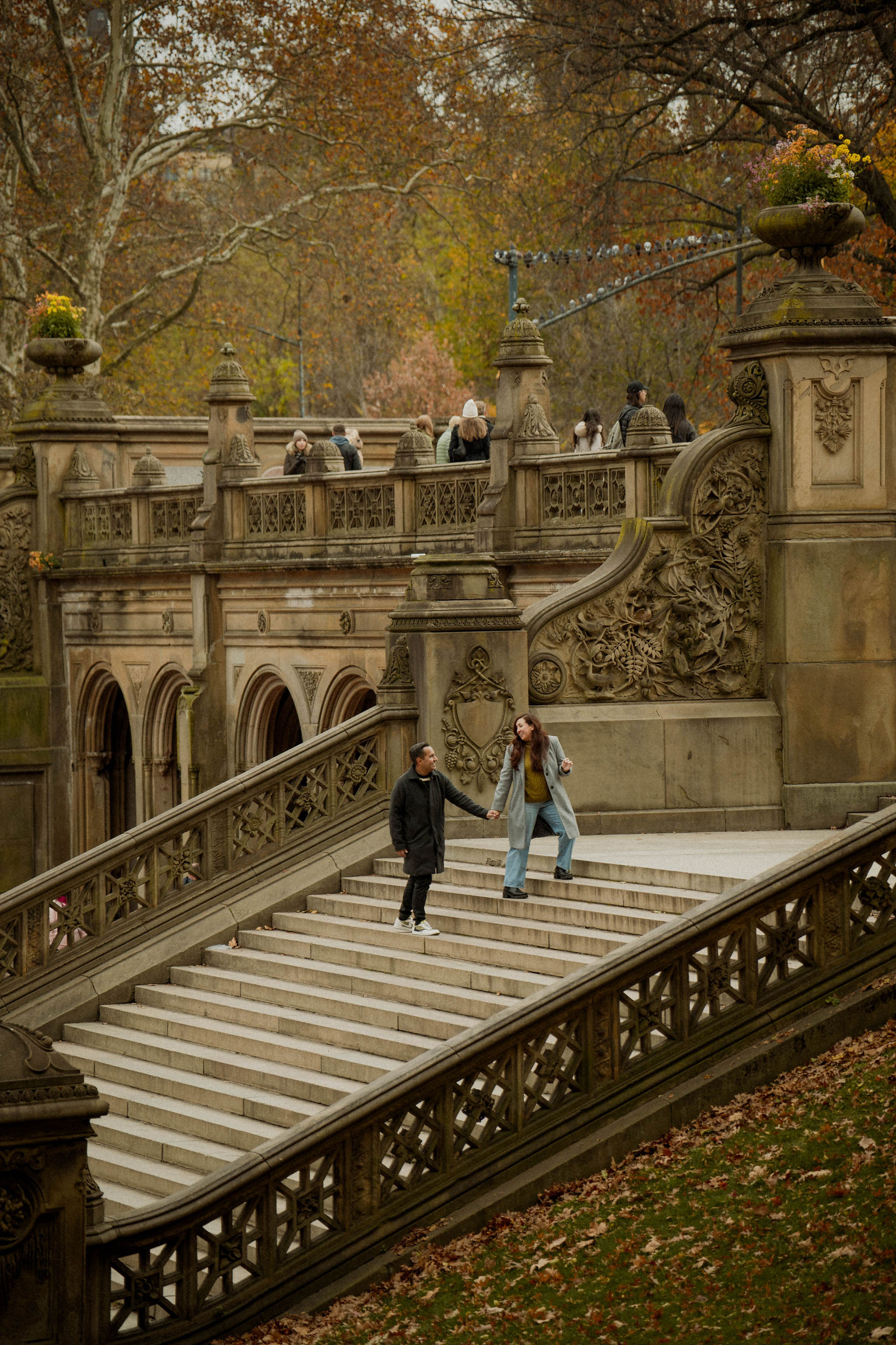 couple during fall engagement photos under peak fall colors in Central Park at Bethesda Terrace staircase