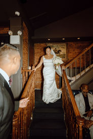bride descending staircase at intimate wedding venue with exposed brick and candlelight