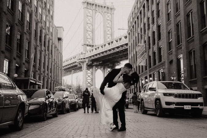 Couple kissing in the middle of Washington Street in DUMBO with Manhattan Bridge framed, Brooklyn elopement photographer capturing iconic NYC wedding photos