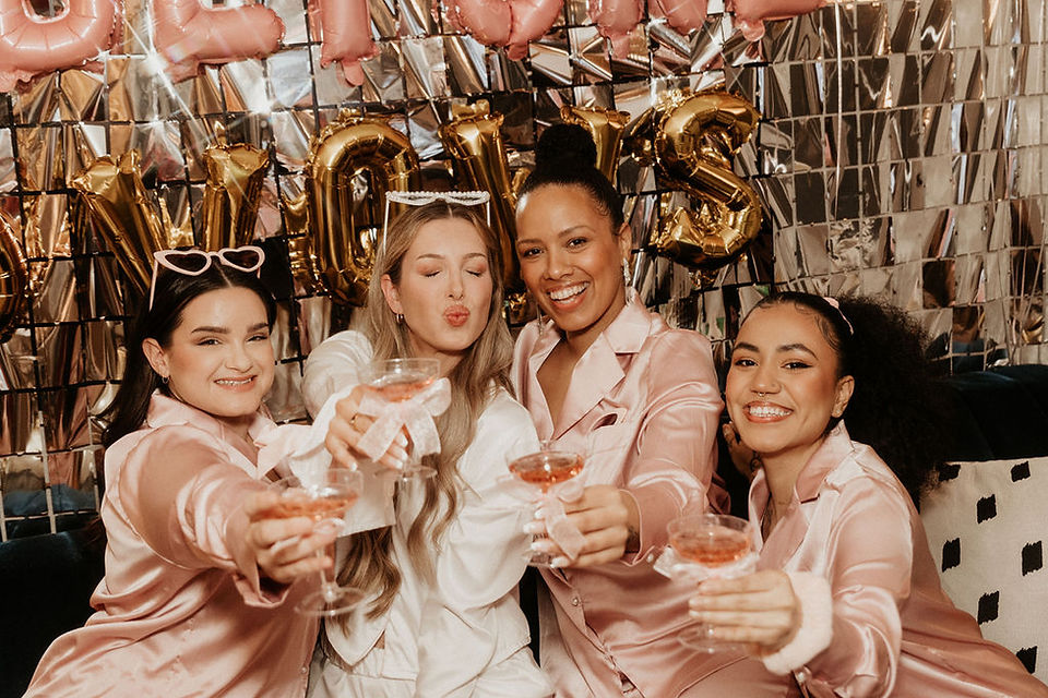 Friendship photo session in NYC with four women in matching pink pajamas celebrating a bachelorette party with gold Veuve Before Vows balloons and decorations