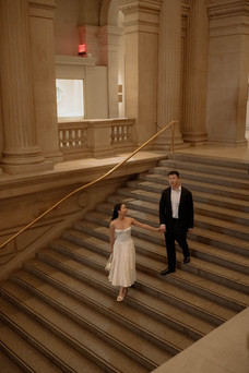 Romantic engagement photoshoot at the Met Museum in New York cinematic dreamy grand staircase, couple holding hands professional couples photography