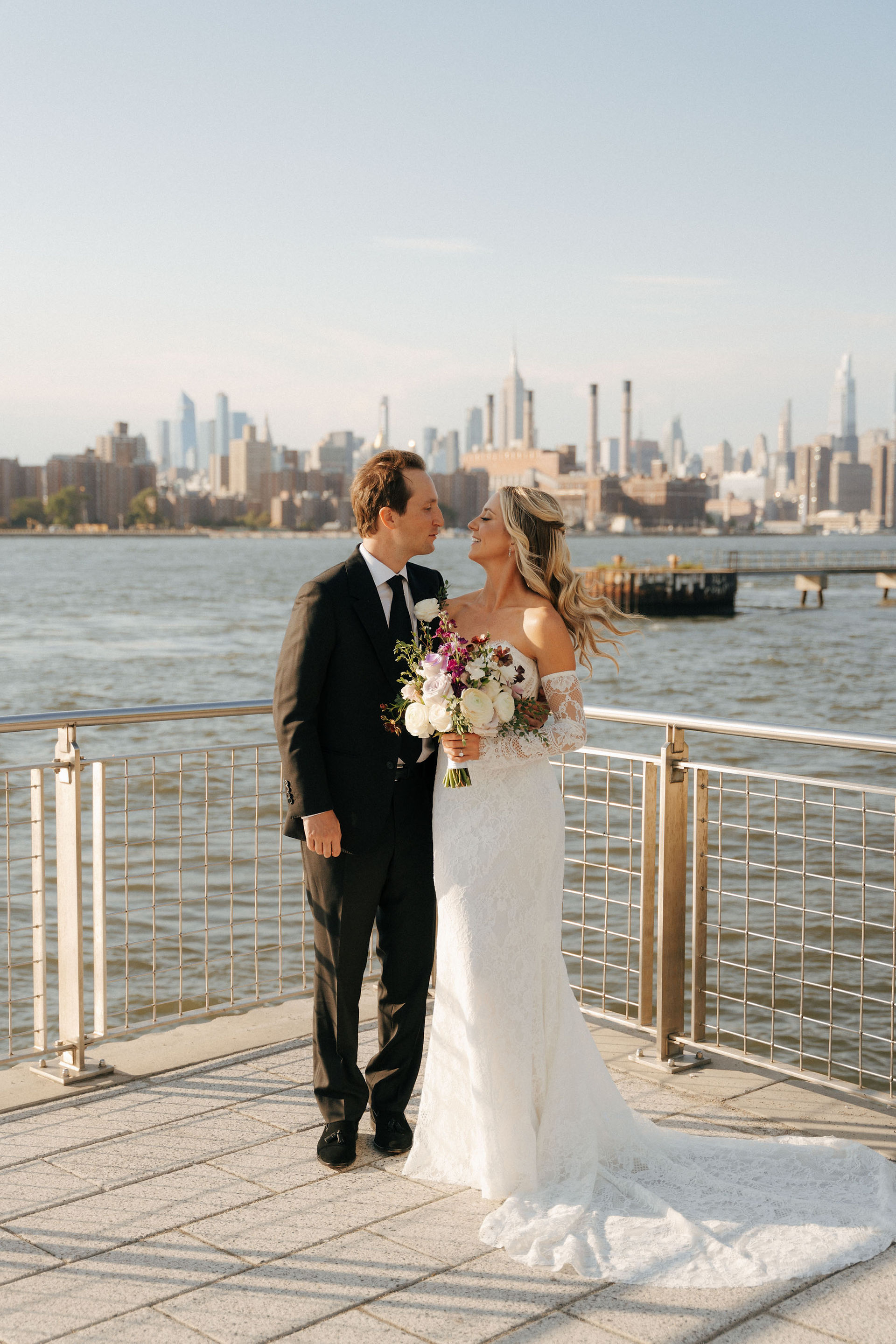 Bride and groom walking hand-in-hand at sunset along Brooklyn waterfront