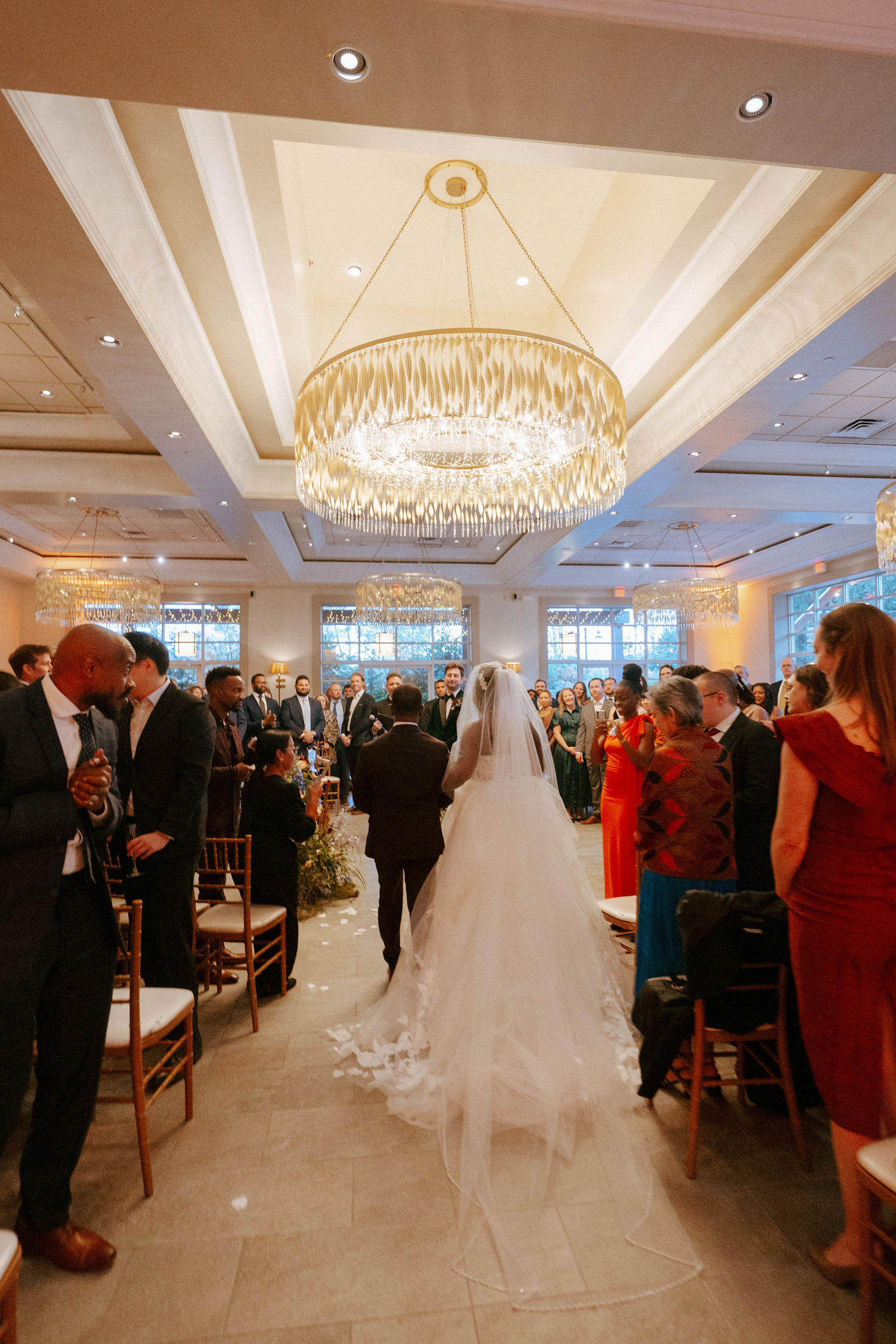 Bride walking down aisle inside luxury New York ballroom wedding venue with grand chandeliers