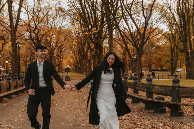 Romantic couple photoshoot in NYC's Central Park, walking hand-in-hand among fall colors at the Literary Walk