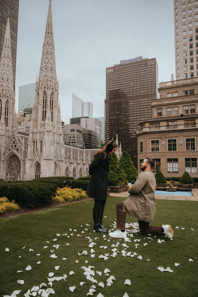 Surprise proposal at 620 Loft and Garden, Rockefeller Center Garden Marriagen proposal, with a Tiffany engagement ring, girl looking at the ring smiling, guy kneeling for proposal, St Patrick’s cathedral o photos