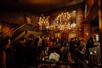 small wedding reception at candlelit venue with chandelier and exposed brick walls