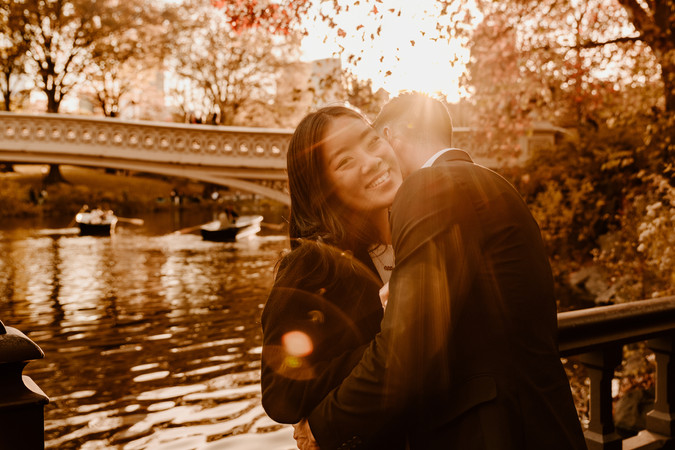 Romantic couple portrait by Bow Bridge NYC with fall colors and cinematic sunlight during engagement photoshoot