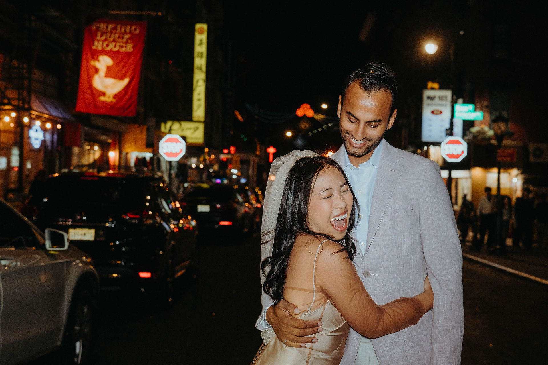 couple hug on chinatown street at night neon lights new york city elopement