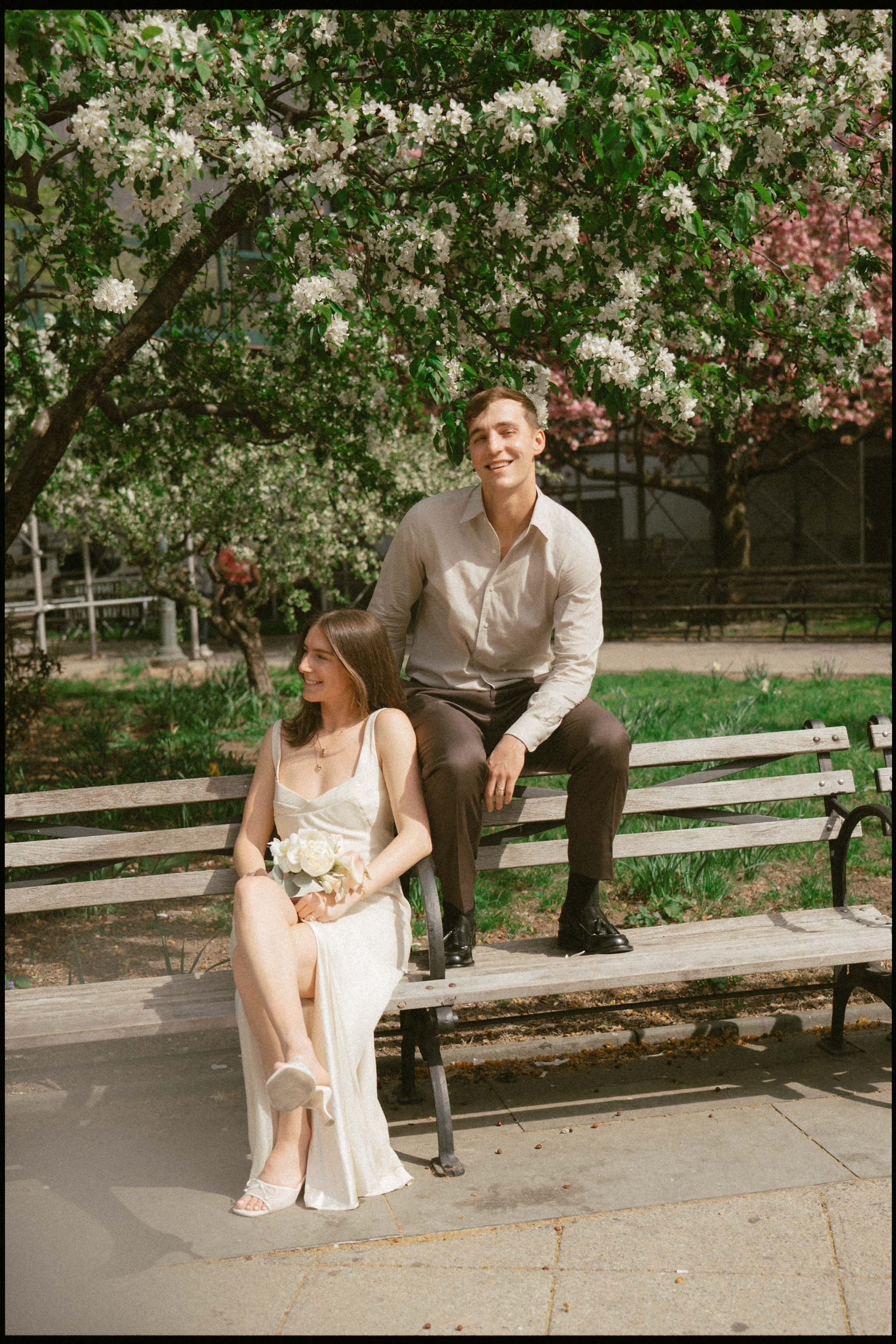 bride and groom sitting on bench in city hall park lower manhattan spring wedding