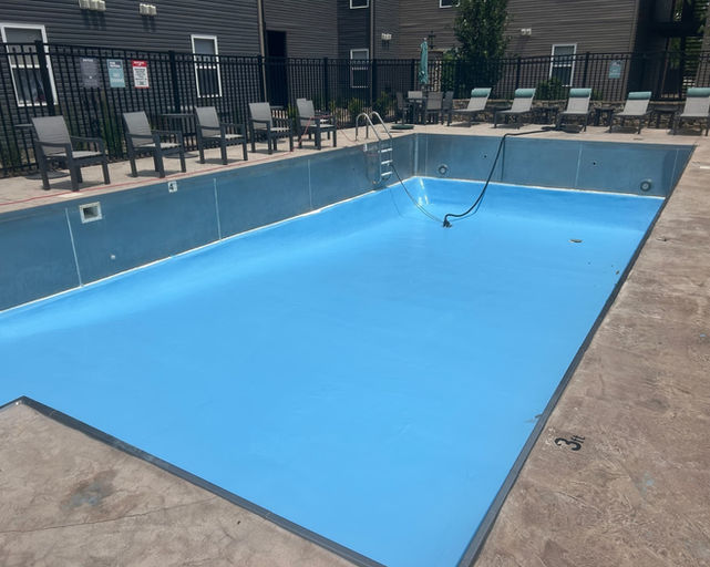 Empty swimming pool with blue lining and lounge chairs