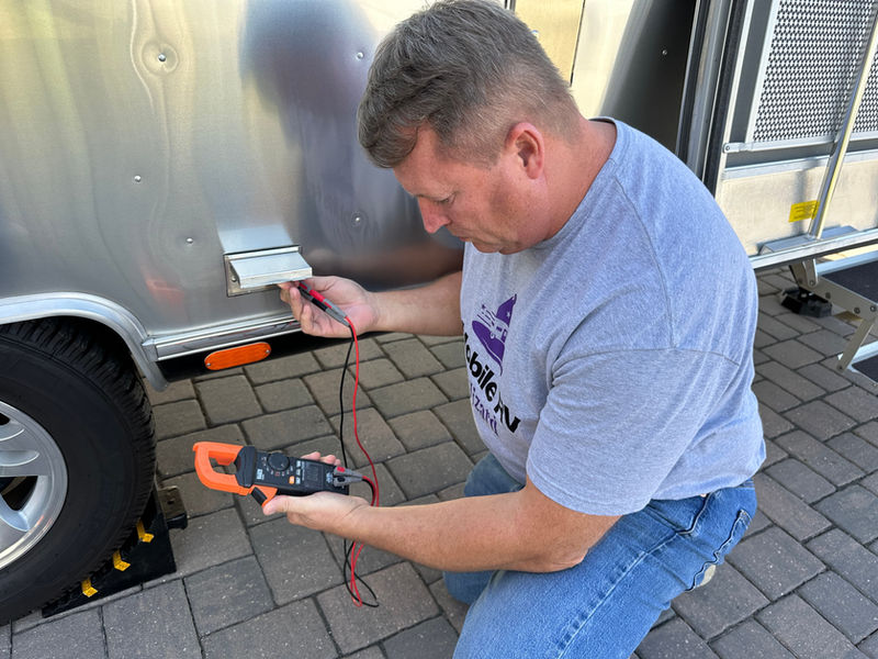 Technician testing an RV shore power connection with a clamp meter