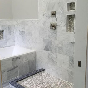 Modern bathroom with walk-in shower, pebble floor, and bathtub