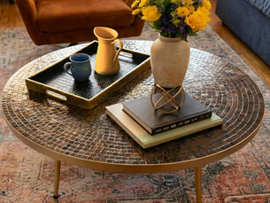 A curated tabletop featuring natural light and warm tones, showing a balanced conversation between a tall vase, textured bowl, and a clear space for a coffee cup.