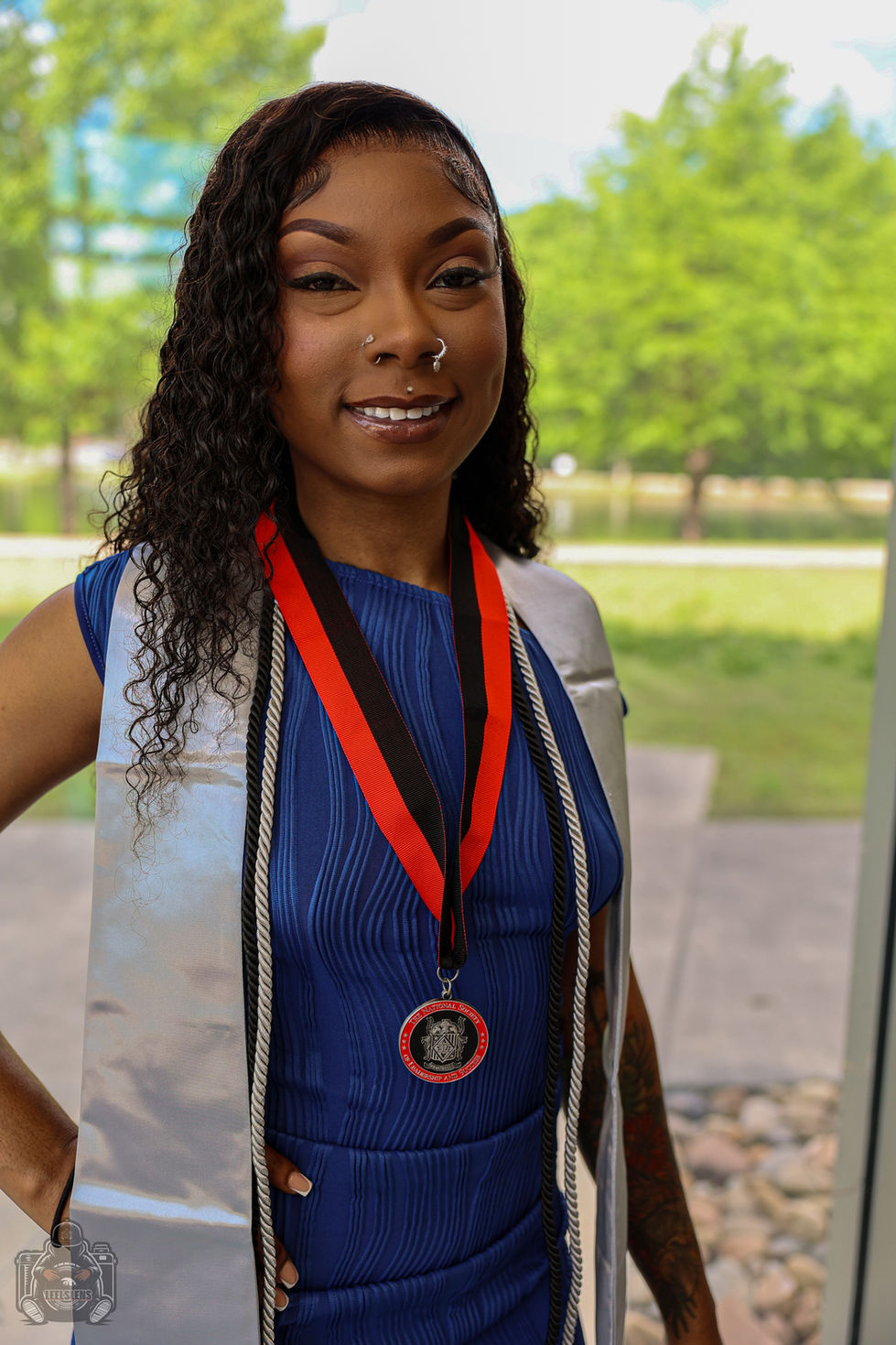 Happy female graduate with silver stole and medal smiling outdoors.