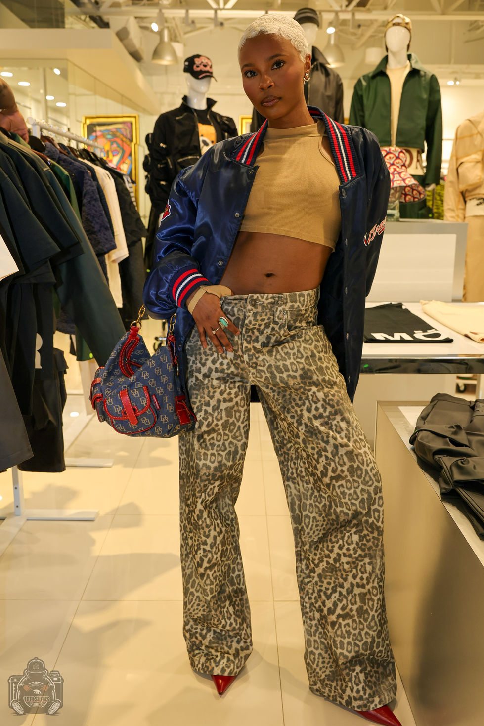Stylish person in tan crop top, blue bomber, leopard print pants.