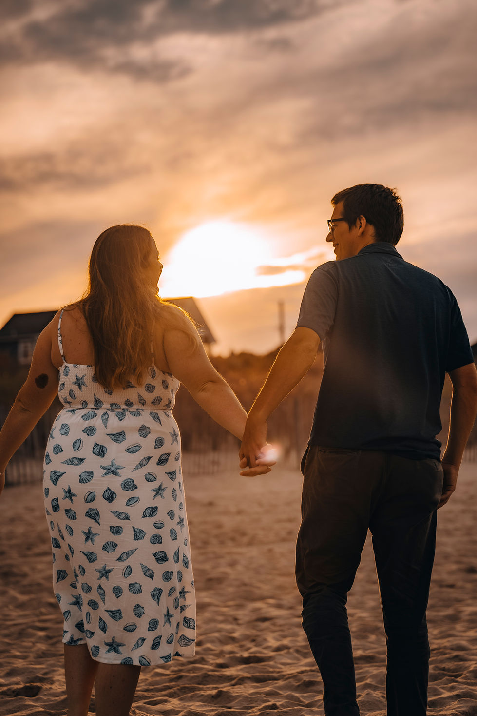 Couple walking with a sunset in front of them at Rehoboth Beach, DE